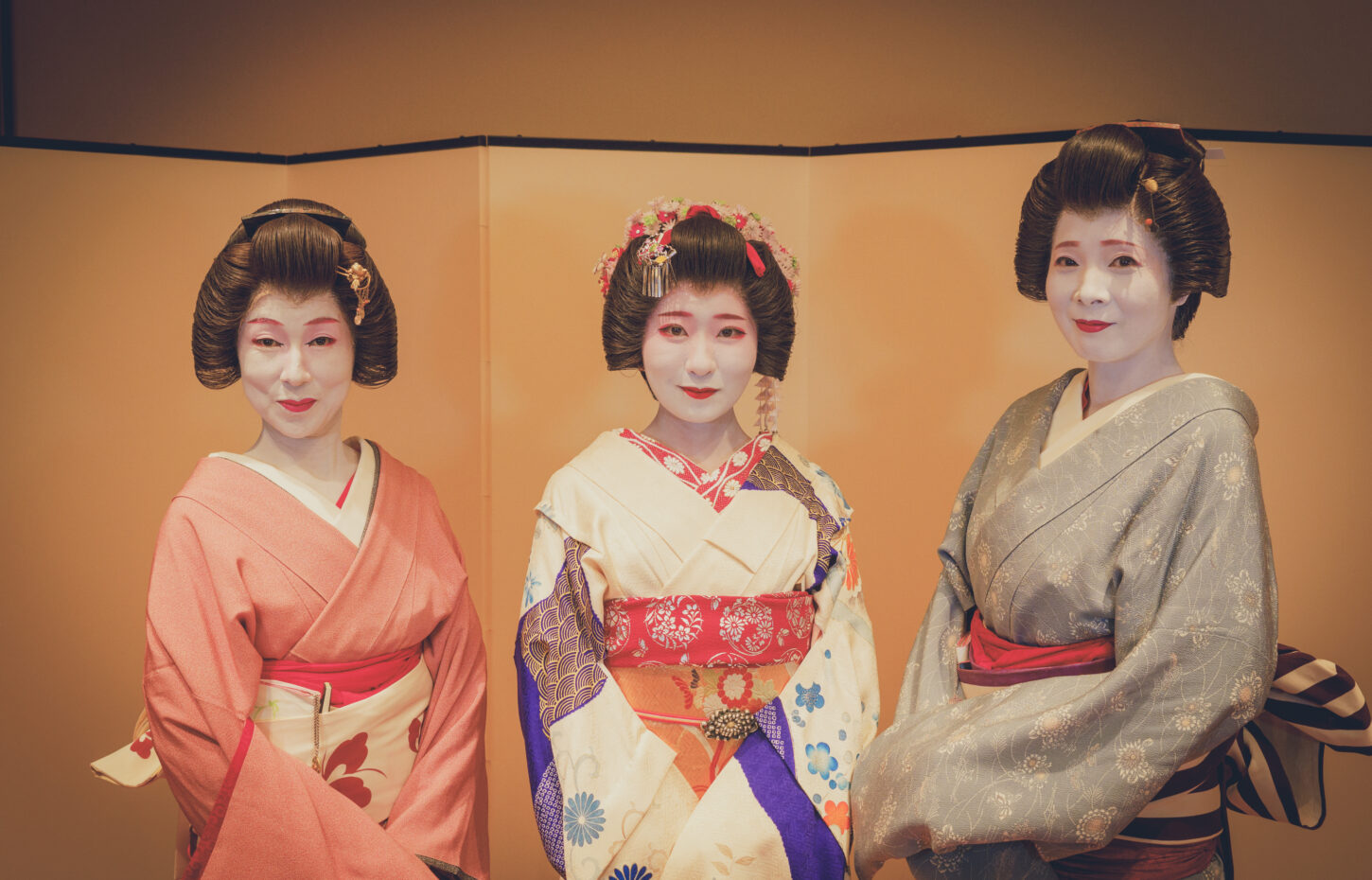 屏風の前に並んで立つ芸者衆3名。中央に半玉が立つ