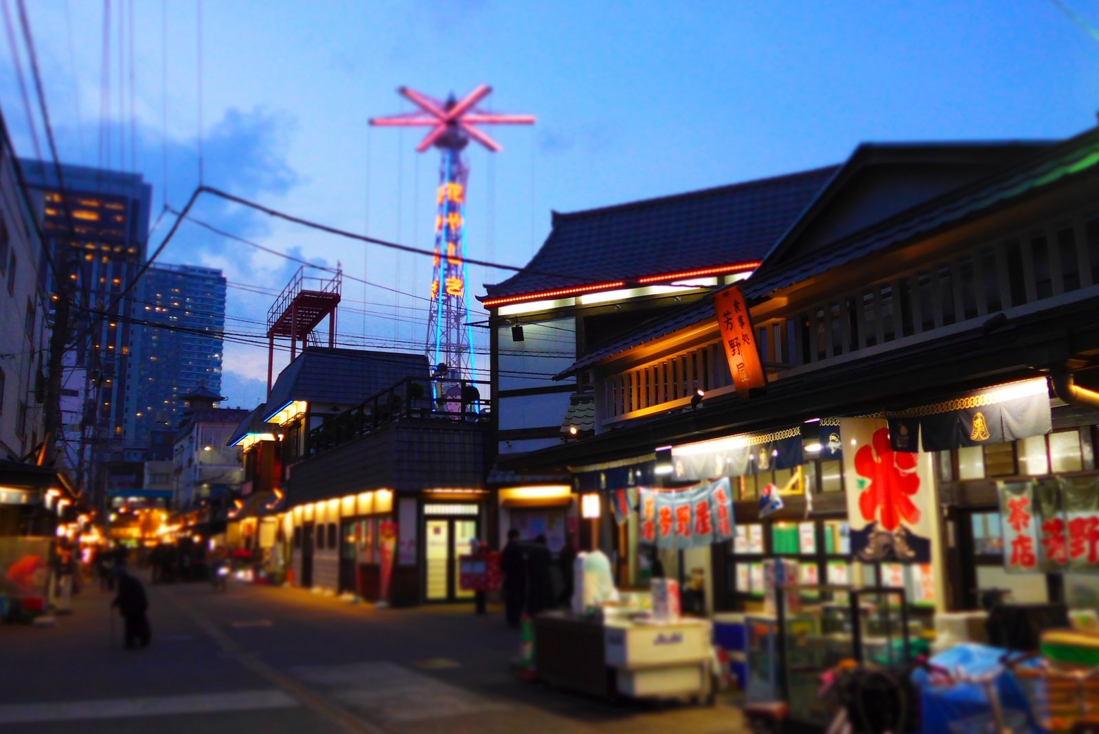 夕暮れの花やしき通り（商店の灯りと遊具の塔）