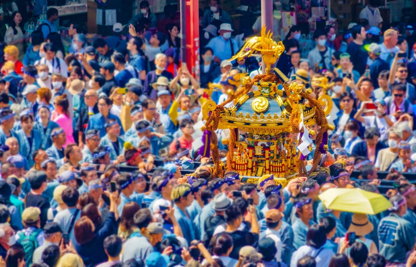 三社祭で担がれる金色の神輿。浅草の街を埋め尽くす担ぎ手と見物客に囲まれている
