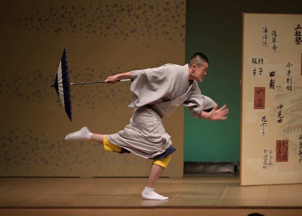 舞台で番傘を手に芸を披露する幇間