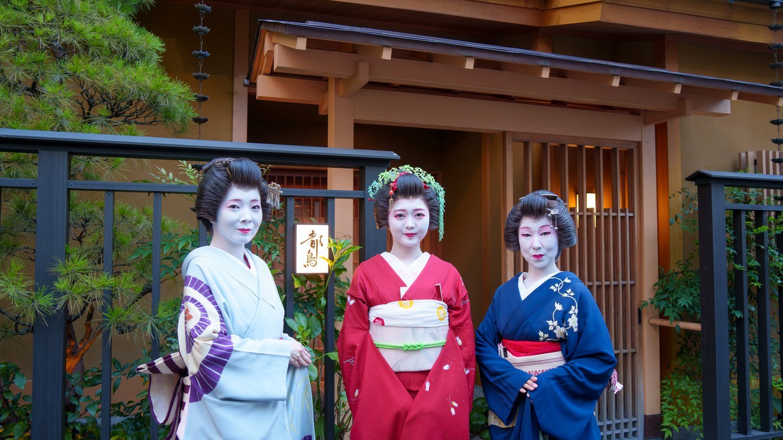 都鳥の玄関前 都鳥の玄関前に立つ芸者3名。夕方の光のなか、格子の店構えを背にしている