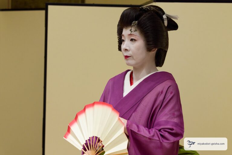 紅白の扇を胸元に構える芸者の横顔