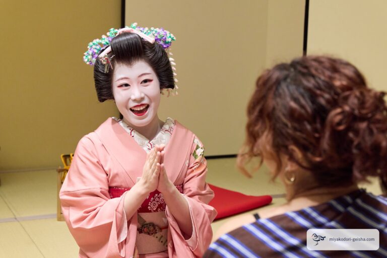 手を合わせて笑顔でお客様に向かう芸者